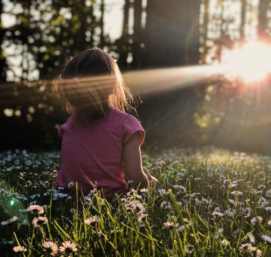 girl sitting on daisy flowerbed in forest